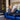 Person sitting on a blue couch reading a magazine with Aquila bags nearby.